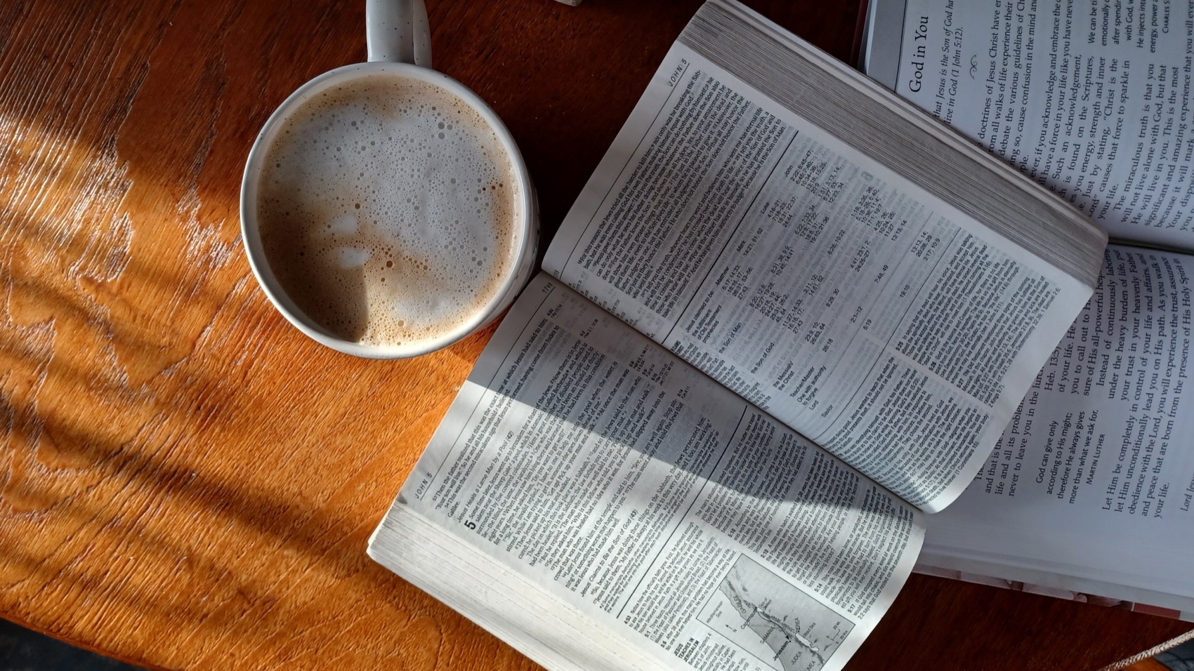 An open Bible and a coffee on a wooden table